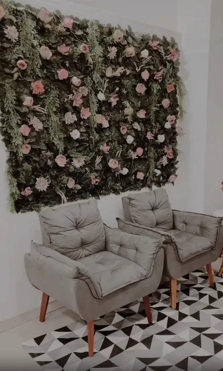Sala de espera do Studio Concept Beauty, com parede de flores e poltronas
